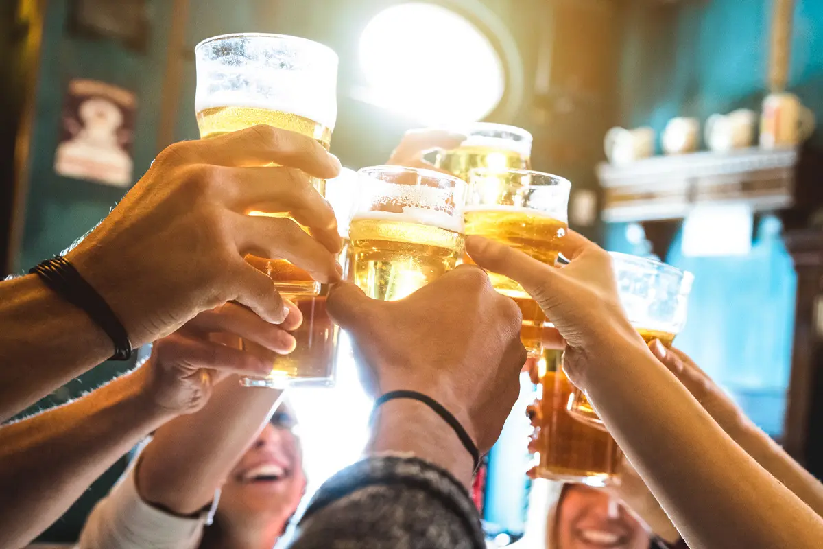 Group of students raising pints of beer together in celebration, highlighting freshers week drinks deals.