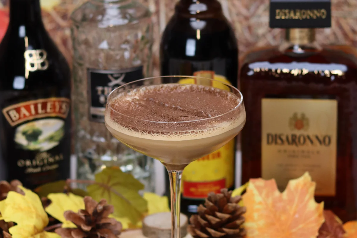 A rich Tiramisu Martini cocktail surrounded by Baileys, Disaronno, and vodka bottles, highlighting early Christmas drinks deals and festive gifting at Bargain Booze.