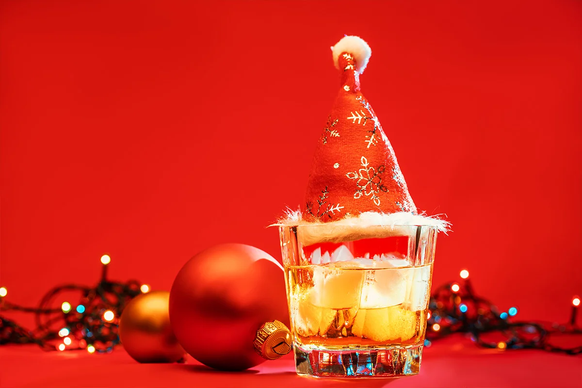 A festive glass of whiskey on ice with a Santa hat and Christmas baubles, celebrating early Christmas drinks deals and festive gifting at Bargain Booze.