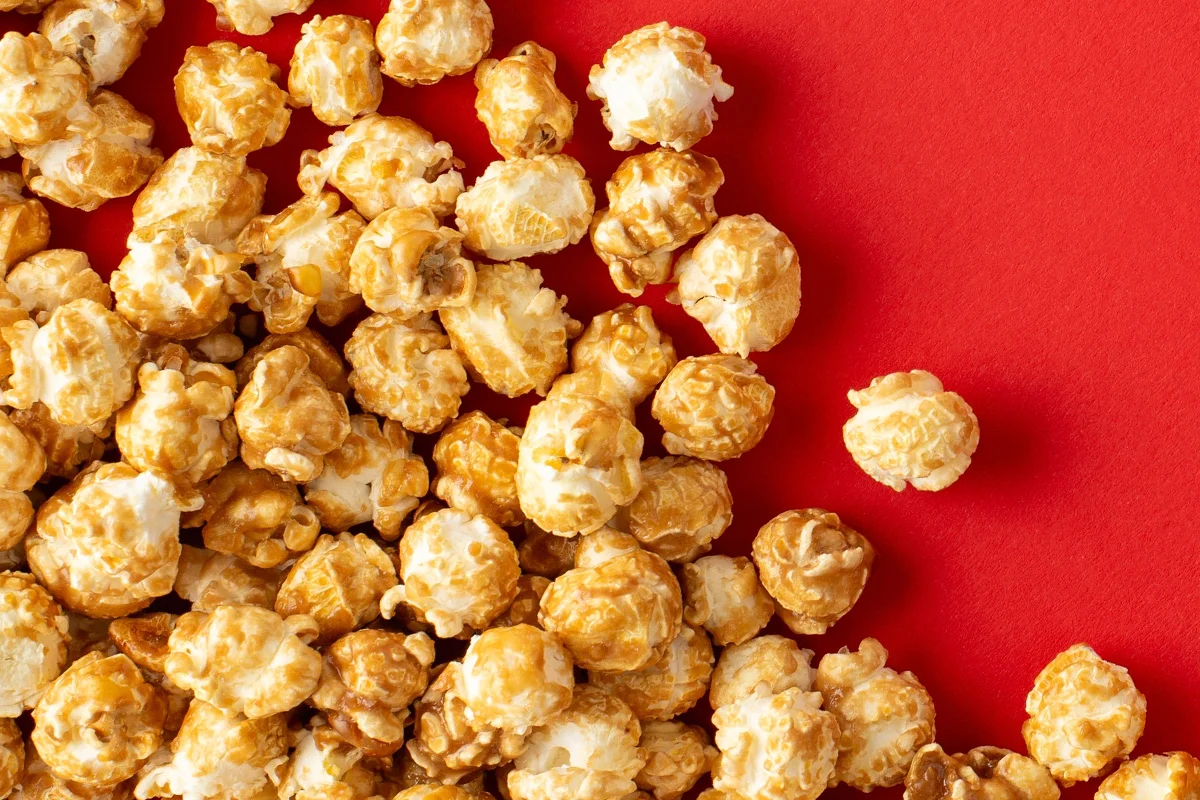 Close-up of golden caramel popcorn on a red background, part of early Christmas drinks deals and festive gifting ideas at Bargain Booze.