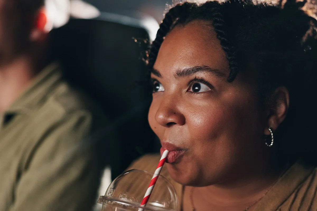 A woman enjoying a festive drink while watching a film, celebrating early Christmas drinks deals and festive gifting at Bargain Booze.