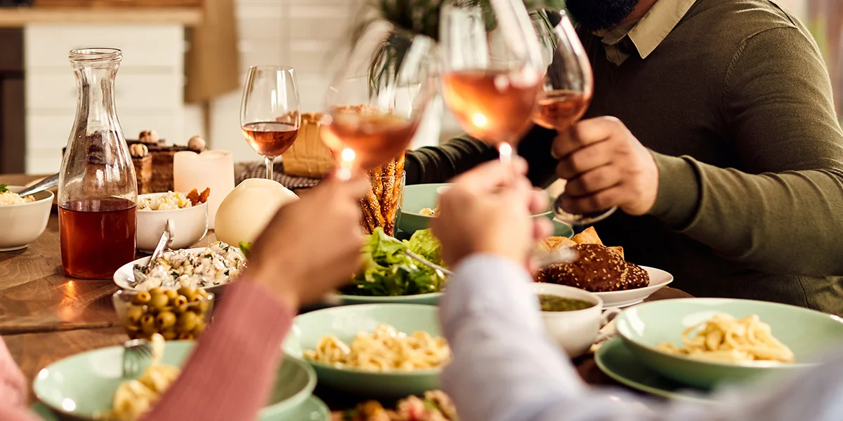 Friends sharing a relaxed dinner at home with food and wine as part of easy Dry January drinks deals