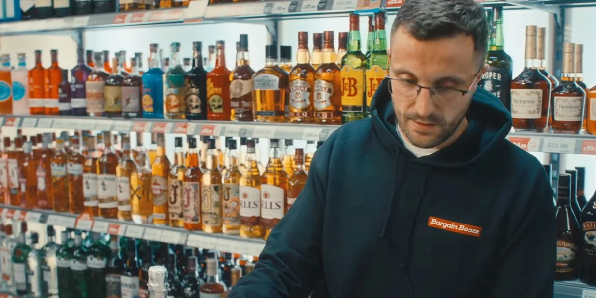 Bargain Booze store team member restocking shelves as customers shop local Dry January drinks deals