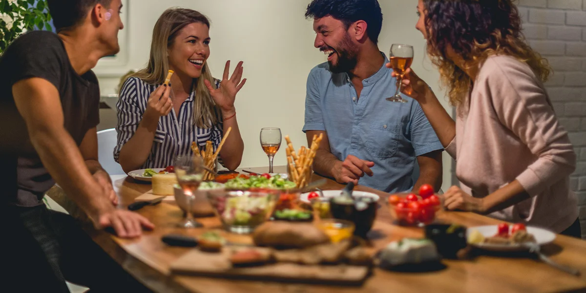 Friends enjoying a relaxed dinner party at home with food and drinks as part of cosy Dry January drinks deals