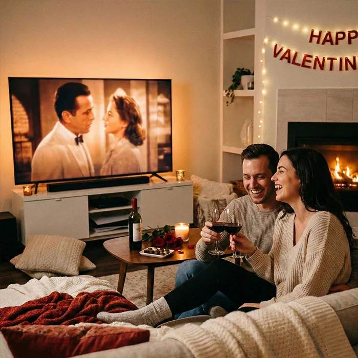 Couple enjoying a cosy Valentine’s night at home with red wine and a film, capturing Cosy Nights In: Comfort Drinks Done Properly