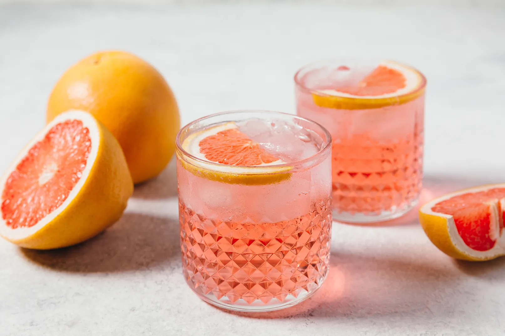 Pink grapefruit cocktail served over ice with fresh grapefruit slices